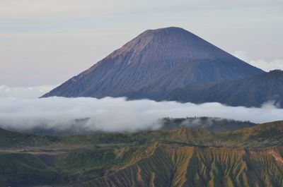 Scenic view of landscape against cloudy sky during sunset