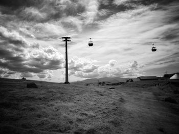 Low angle view of overhead cable car on field against sky