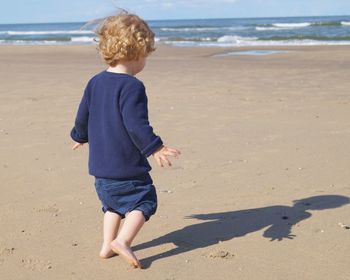 Full length of boy on beach against sky