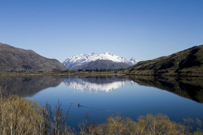 Scenic view of lake and mountains against clear blue sky