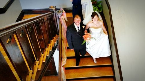 Portrait of smiling bride and groom walking on steps during wedding ceremony