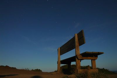 Built structure on field against clear blue sky at night