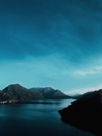 Scenic view of sea and mountains against blue sky