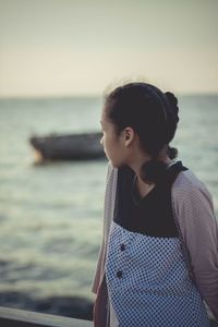 Thoughtful woman standing against sea during sunset