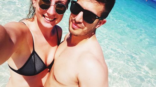 Portrait of couple wearing sunglasses in sea