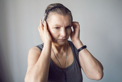 Woman aged athlete listens to music through headphones during gymnastics