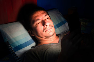 Man using mobile phone while lying in bed