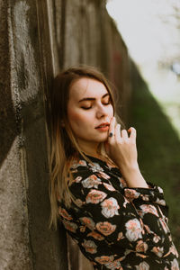 Portrait of a beautiful young woman standing against wall