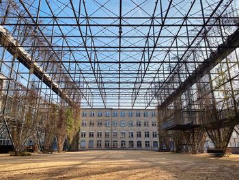 Bare trees in abandoned building against sky