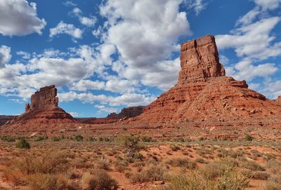 Landscape of desert plants and two buttes vertical rock formations or monoliths