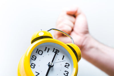 Close-up of hand holding yellow clock