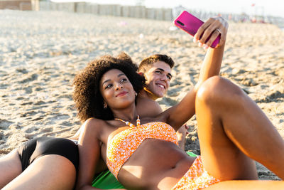 Young woman using mobile phone while sitting on beach