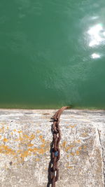 High angle view of rusty metal on rock by sea