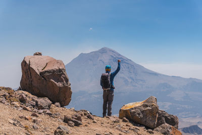 Rear view of man standing on mountain against sky