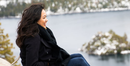 Woman laughing while sitting on land in winter