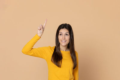 Portrait of smiling young woman against gray background