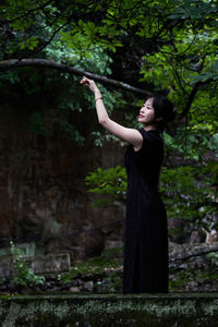 Portrait of young woman standing against trees