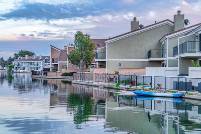 Boats moored on river by buildings against sky