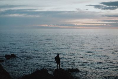 Silhouette of man looking at sea against sky