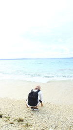 Rear view of man sitting on beach