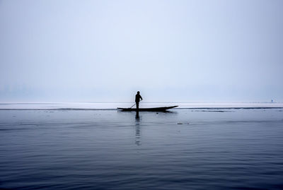 Silhouette man in sea against sky