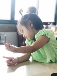 Cute girl pointing at table in home