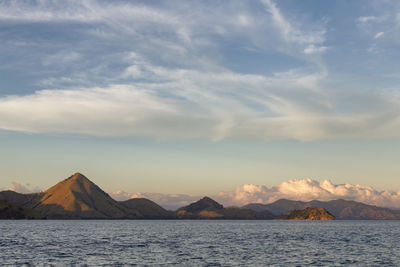 Scenic view of sea by mountains against sky