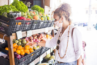 Woman wearing mask standing at vegetable store