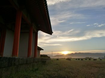 House on field against sky during sunset