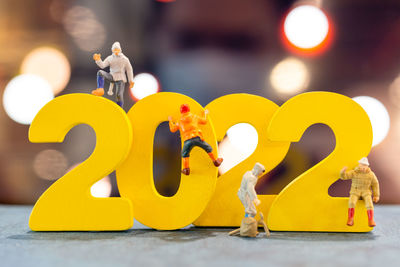 Miniature people climbing up on wooden with number 2022, happy new year concept