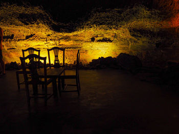 Chairs and table against trees at night
