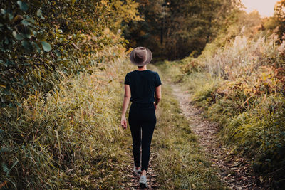 Rear view of woman walking on footpath amidst plants