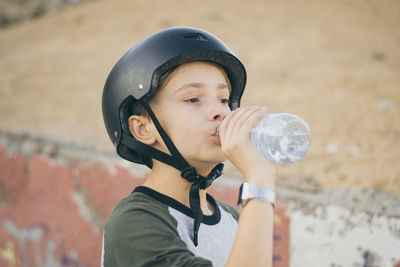 Boy wearing skateboard helmet drinking water