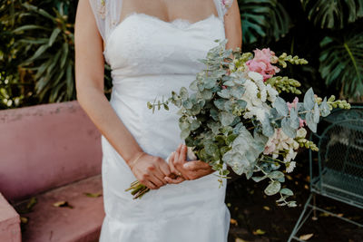 Midsection of bride holding bouquet