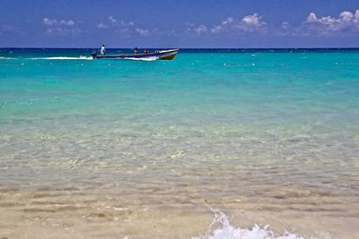 People on boat in sea against sky during sunny day