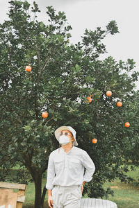 Full length of man standing by tree against orange sky