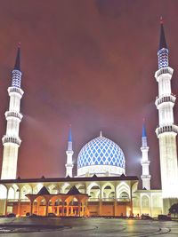 Illuminated sultan salahuddin abdul aziz mosque against sky in city at night