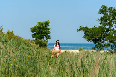 Young adult woman walking in field of reed by sea shore