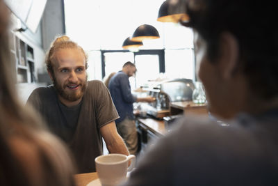 Smiling barista talking with customers in cafe