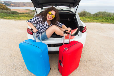 Portrait of young woman sitting on car