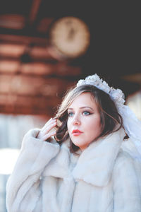 Portrait of young woman standing against wall