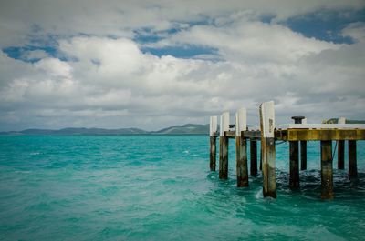 Pier on sea against cloudy sky