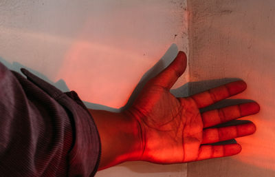 Close-up of hand against red wall