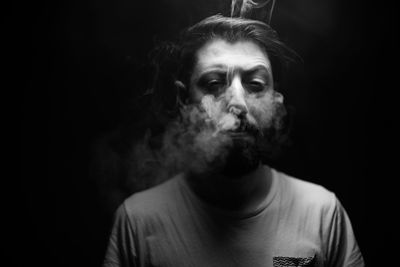 Portrait of man smoking against black background