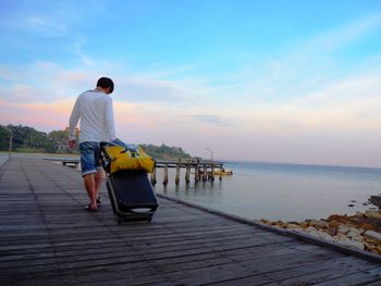 Rear view of man standing on sea shore against sky