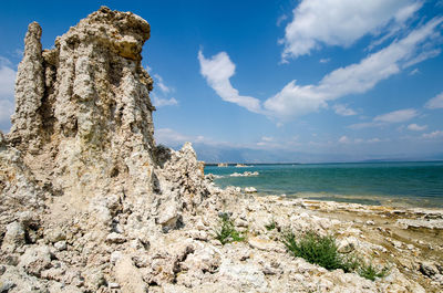 Rock formation on beach against sky