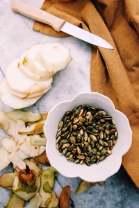 High angle view of pealed and sliced pear and a bowl of nuts