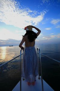 Rear view of woman standing on boat in sea