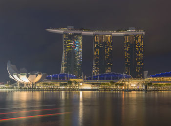Illuminated city by river at night