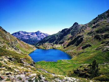 Scenic view of lake and mountains against clear blue sky